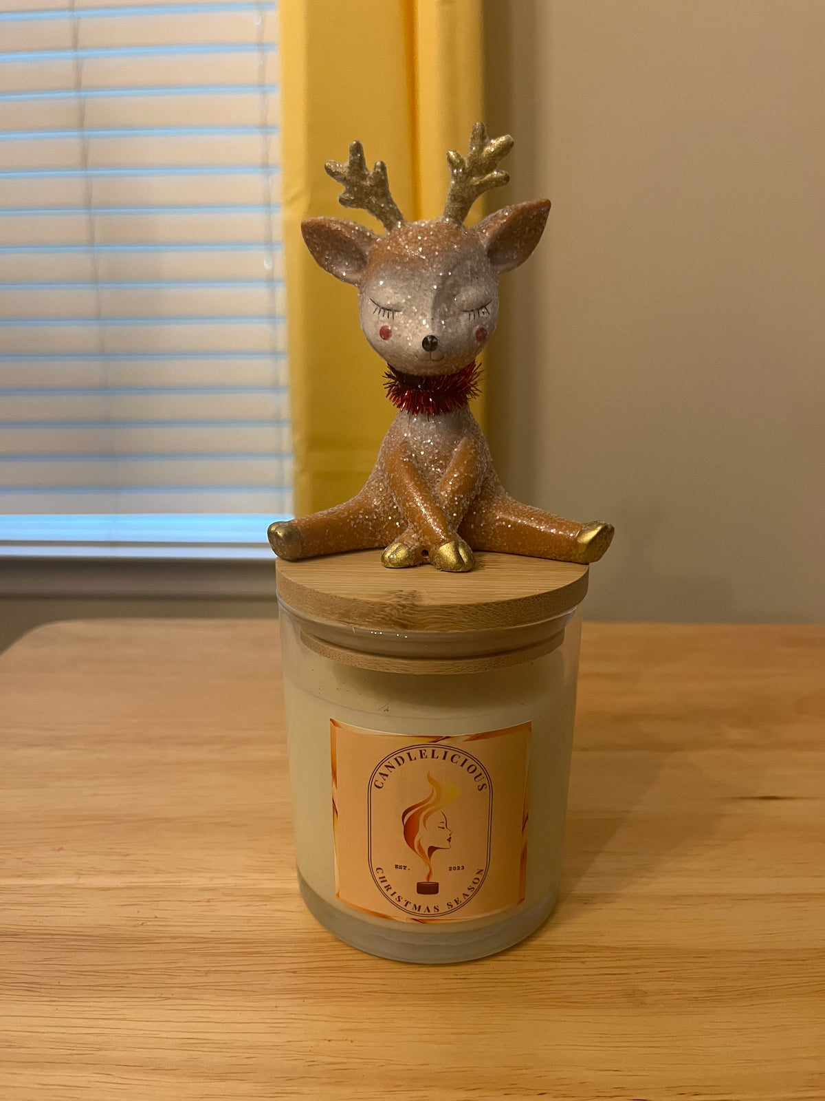 Christmas Season candle with a glittered sitting reindeer, eyes closed, on the lid