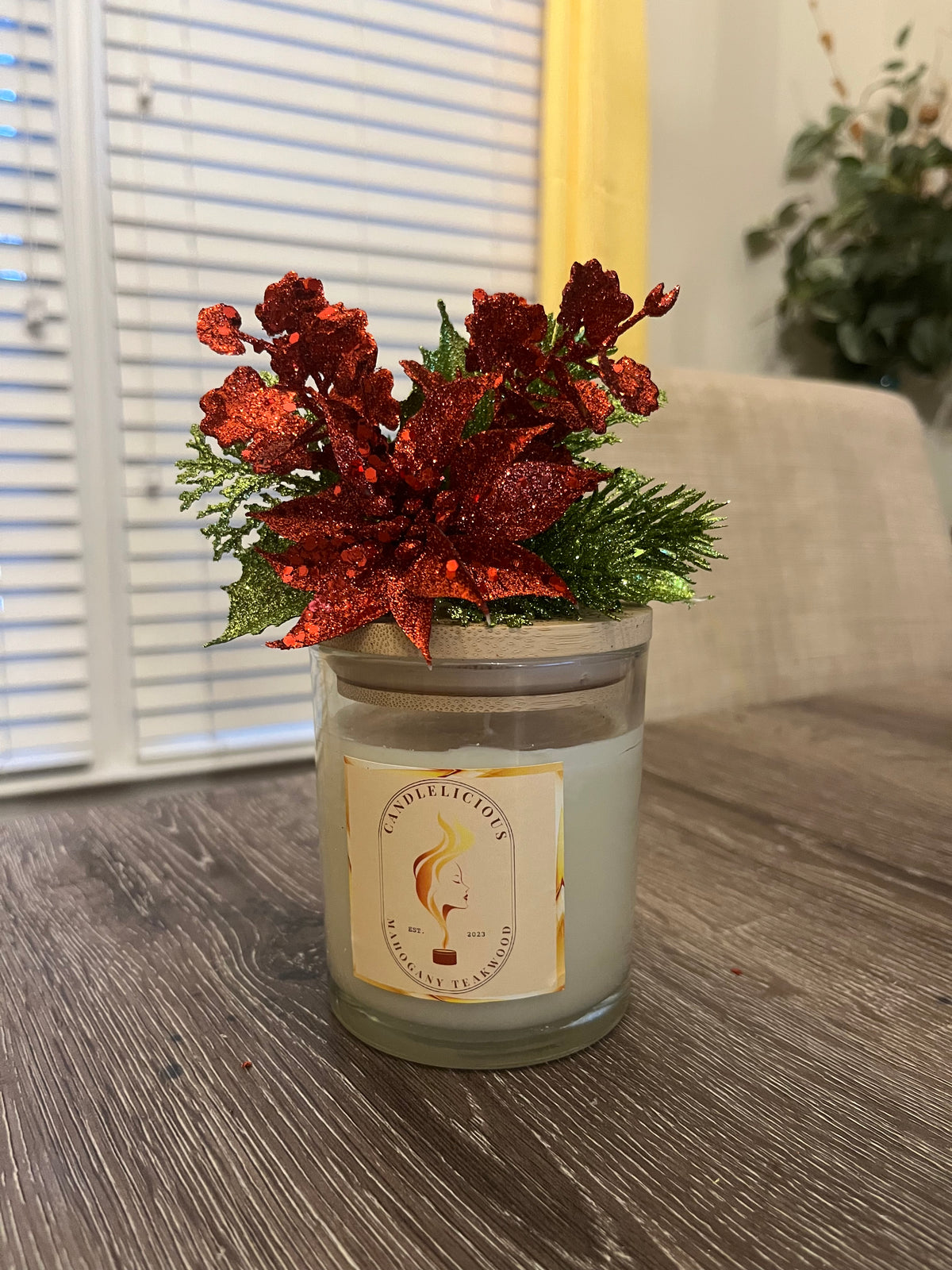 Mahogany Teakwood candle with a red glitter poinsettia and pine on the lid