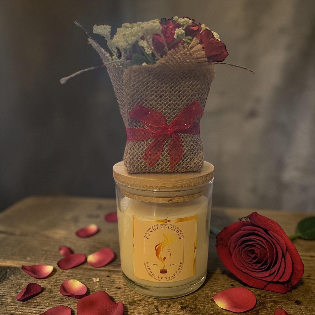 Mahogany Teakwood candle with a bouquet wrapped in burlap on the lid, photographed at home