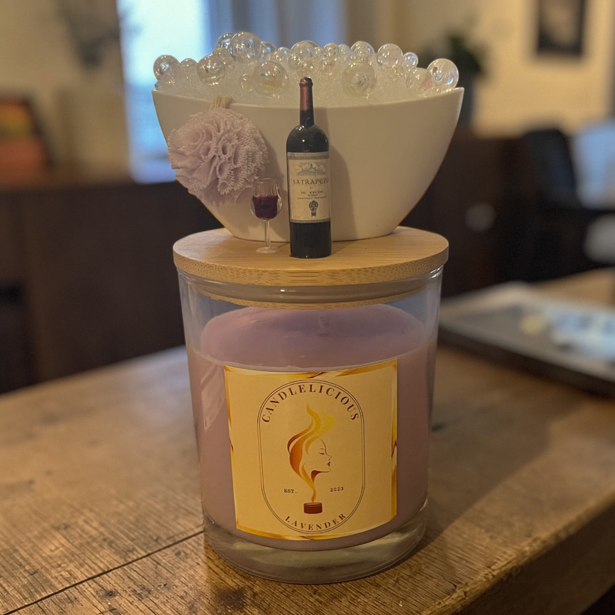 Lavender candle with a bubble bath and a bottle of red wine on the lid, photographed at home