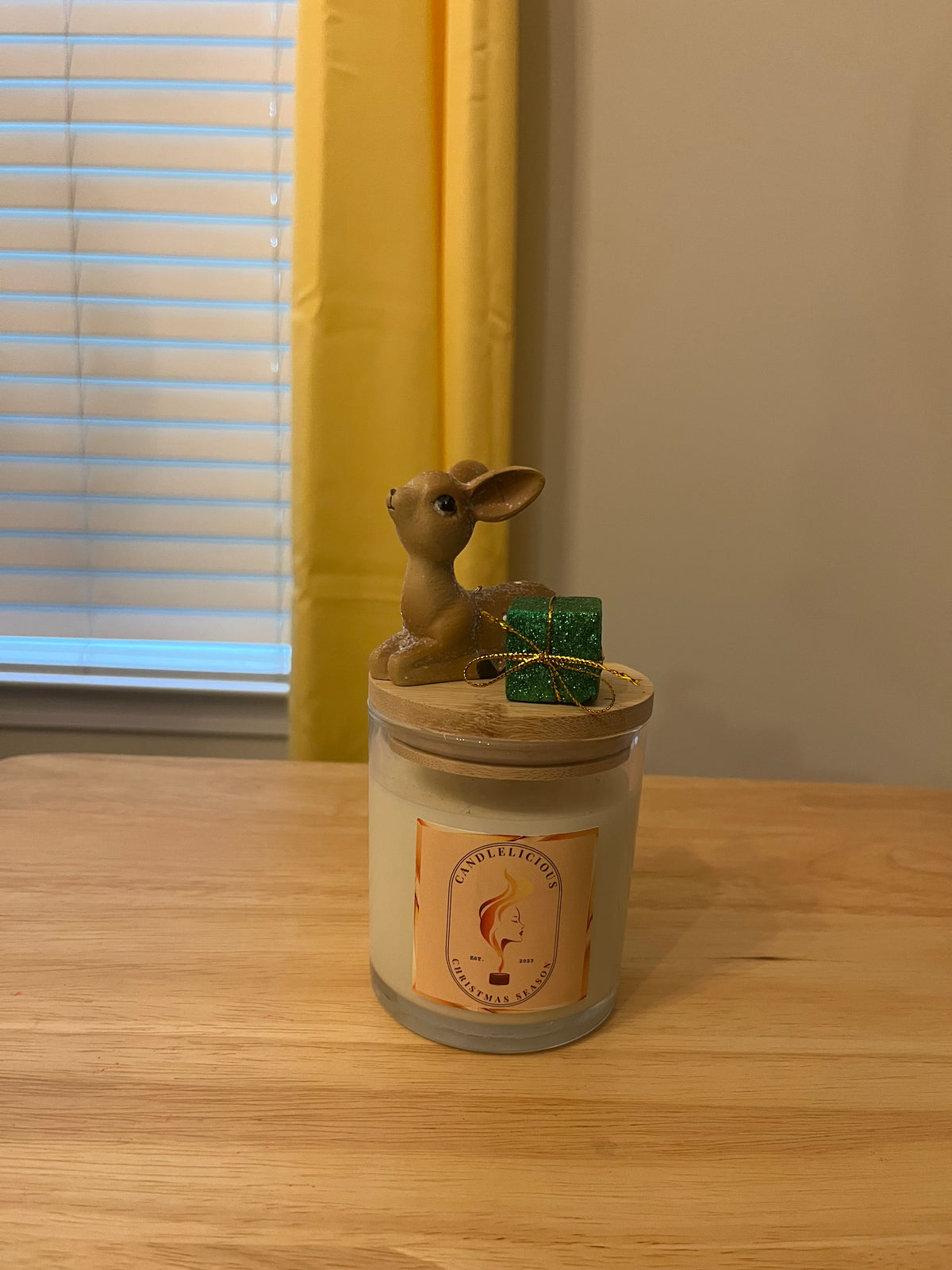 Christmas Season candle with a small fawn and a green gift box on the lid