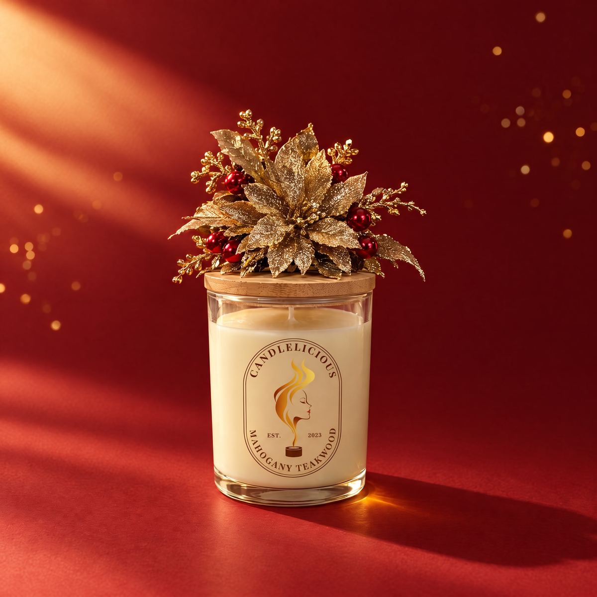Mahogany Teakwood candle with a gold glitter poinsettia on the lid, on a cranberry backdrop