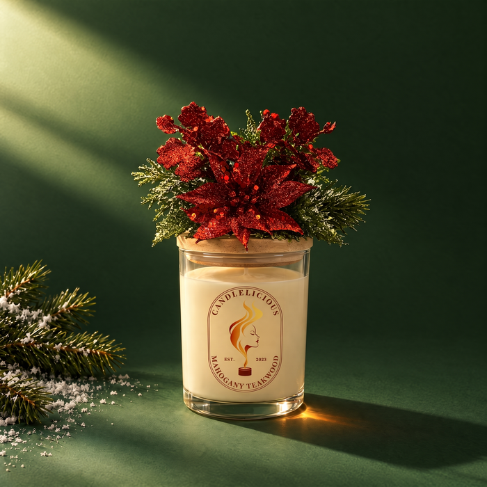 Mahogany Teakwood candle with a red glitter poinsettia on the lid, on an evergreen backdrop