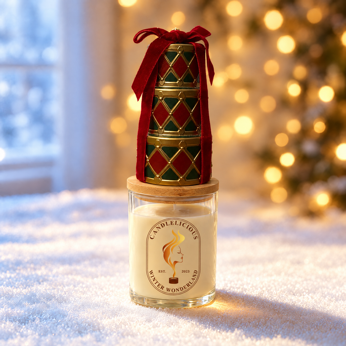 Winter Wonderland candle with a stack of red and green gift tins on the lid, standing in snow