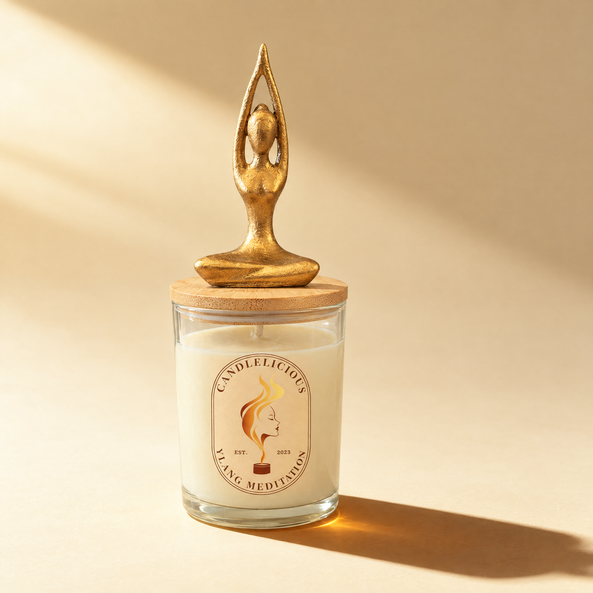 Ylang Meditation candle with a gold seated yoga figure, arms raised, on the lid