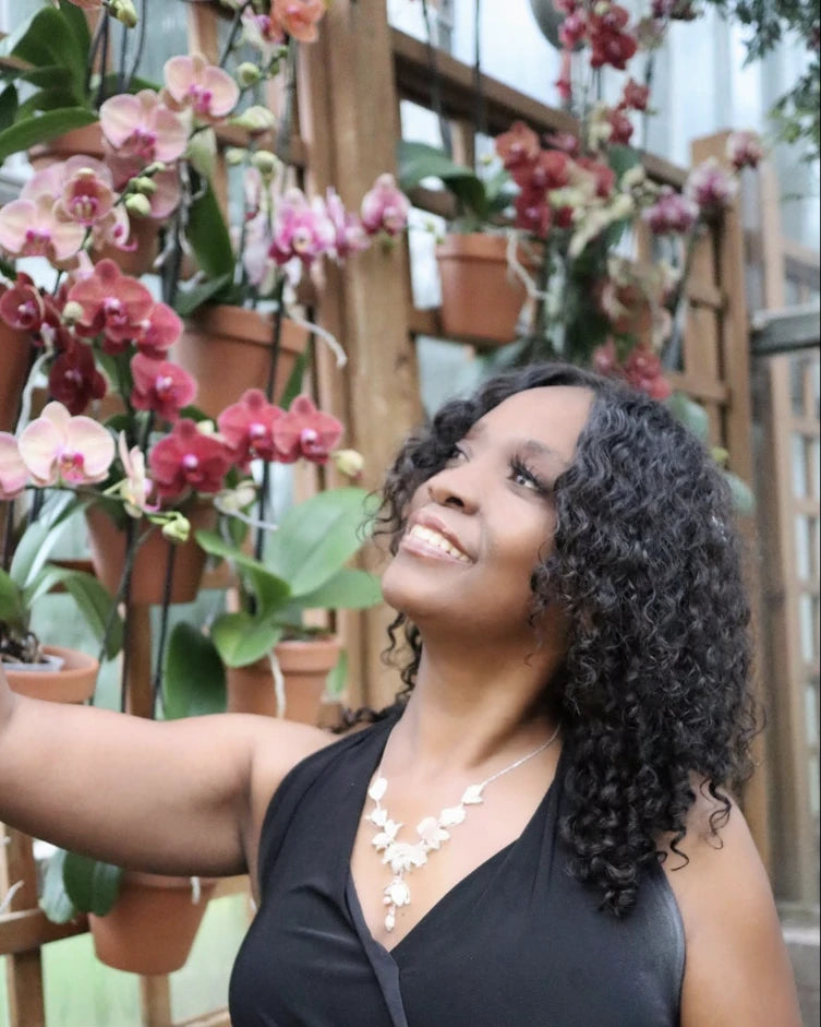 Sherrie smiling up at a wall of orchids
